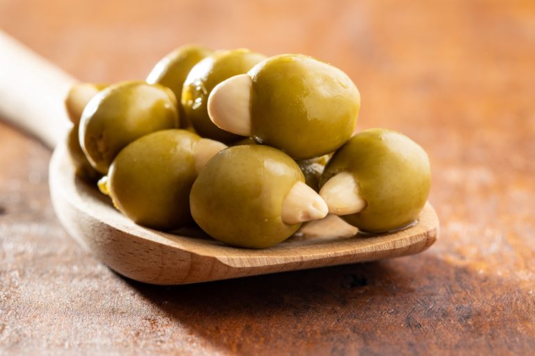 Olive verdi snocciolate ripiene di mandorle su cucchiaio di legno